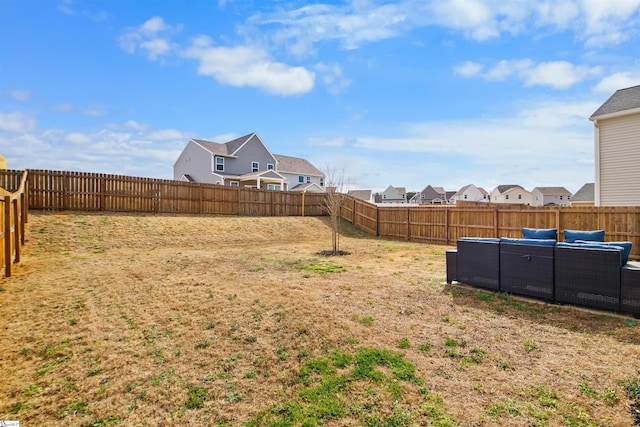 view of yard with a residential view, a fenced backyard, and an outdoor living space