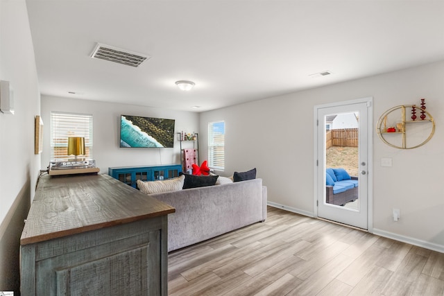 living room featuring a wealth of natural light, visible vents, and light wood-style floors