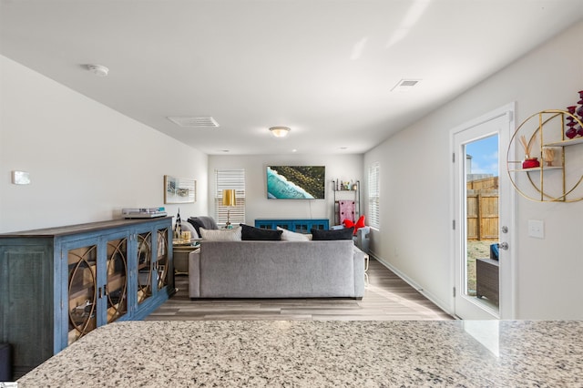 living room featuring wood finished floors, visible vents, and baseboards