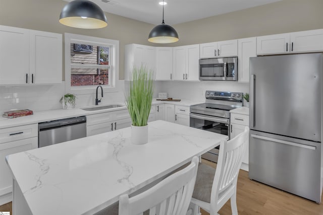 kitchen with tasteful backsplash, appliances with stainless steel finishes, a sink, and white cabinets