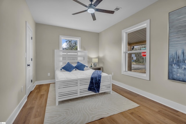 bedroom featuring ceiling fan, wood finished floors, visible vents, and baseboards