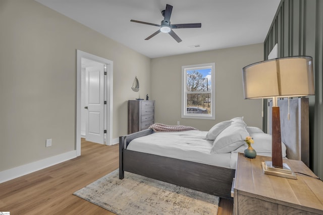 bedroom with light wood finished floors, visible vents, baseboards, and a ceiling fan