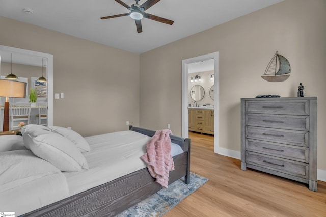 bedroom with ceiling fan, ensuite bath, light wood-style flooring, and baseboards