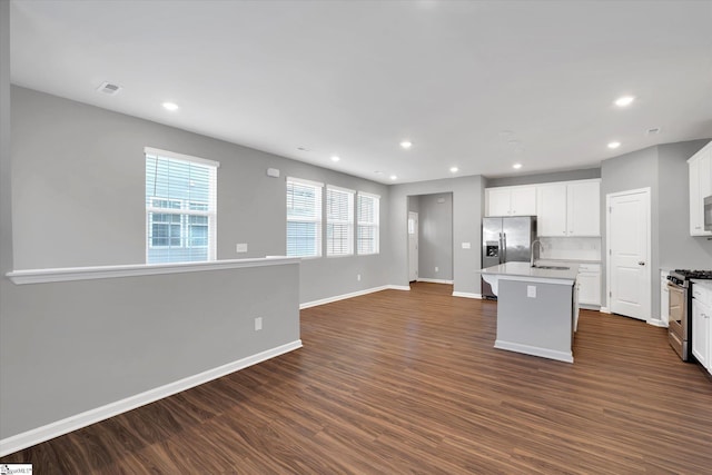 kitchen featuring dark wood finished floors, a center island with sink, stainless steel appliances, open floor plan, and a sink