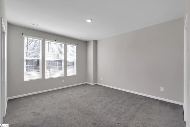 spare room with carpet, visible vents, and baseboards