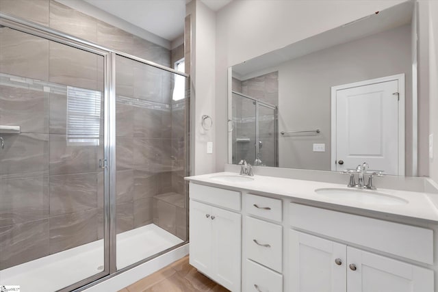 bathroom with a stall shower, a sink, and double vanity