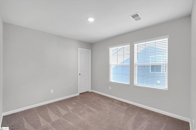 spare room with carpet flooring, visible vents, and baseboards