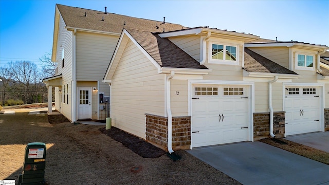 view of side of home with a shingled roof, driveway, and an attached garage