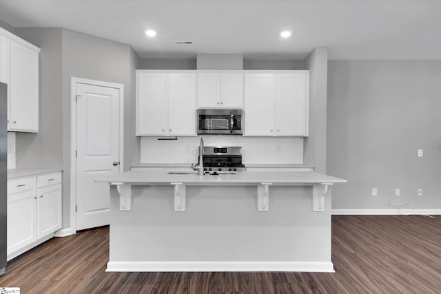 kitchen featuring stainless steel appliances, visible vents, dark wood-type flooring, a sink, and baseboards