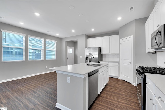 kitchen with dark wood-style floors, visible vents, appliances with stainless steel finishes, a sink, and an island with sink