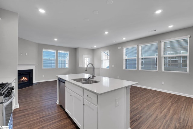 kitchen with dark wood finished floors, light countertops, appliances with stainless steel finishes, open floor plan, and a sink