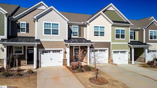 multi unit property with driveway, a standing seam roof, and stone siding