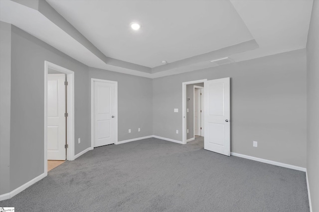 carpeted spare room featuring baseboards, a raised ceiling, and recessed lighting