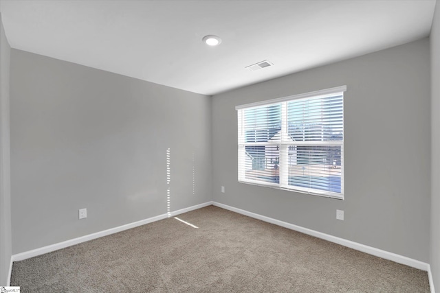 unfurnished room featuring carpet floors, visible vents, and baseboards