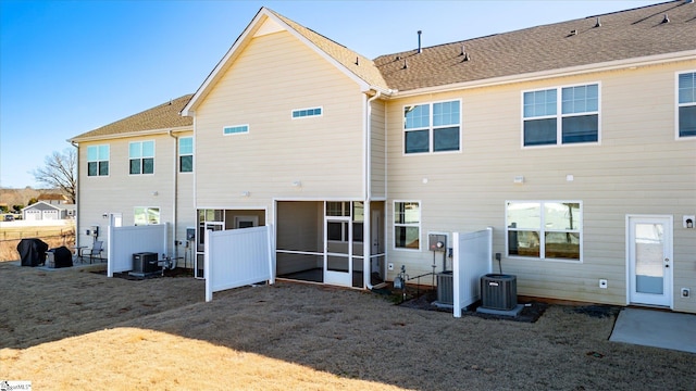 rear view of house with central AC, roof with shingles, and fence