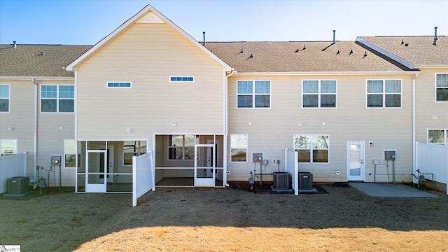 back of property with central AC unit, a sunroom, fence, and a yard