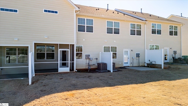 rear view of property with central AC unit and a lawn