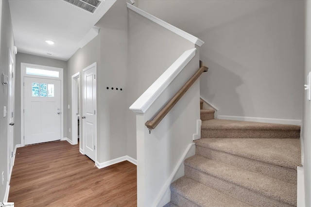 stairs featuring visible vents, baseboards, and wood finished floors