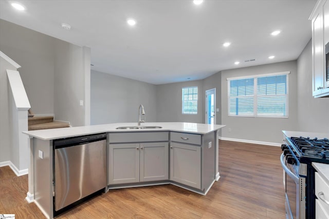 kitchen featuring appliances with stainless steel finishes, light countertops, a sink, and gray cabinetry