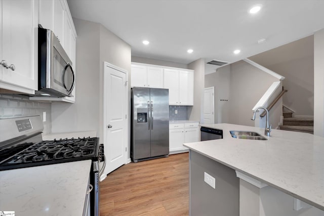 kitchen featuring stainless steel appliances, light wood-type flooring, white cabinets, and a sink