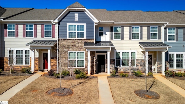 townhome / multi-family property featuring stone siding, roof with shingles, and a standing seam roof