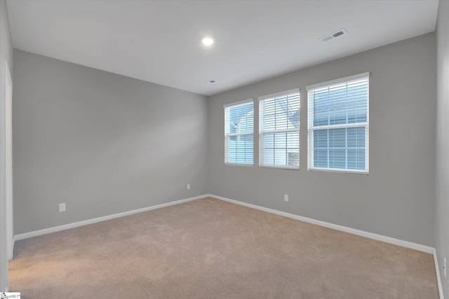 spare room with light carpet, baseboards, and visible vents