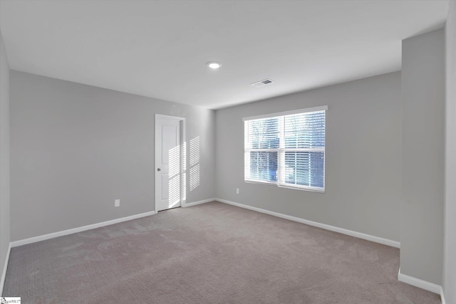 spare room featuring baseboards, visible vents, and carpet flooring