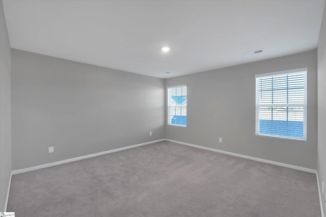 spare room featuring baseboards, visible vents, a wealth of natural light, and carpet flooring