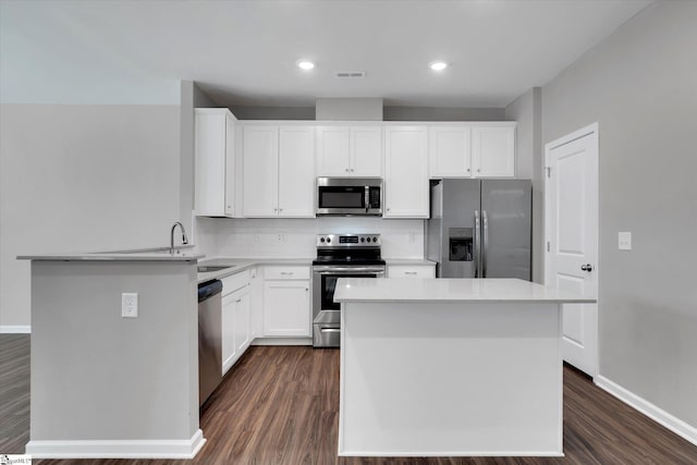 kitchen with white cabinetry, a kitchen island, appliances with stainless steel finishes, and dark wood finished floors