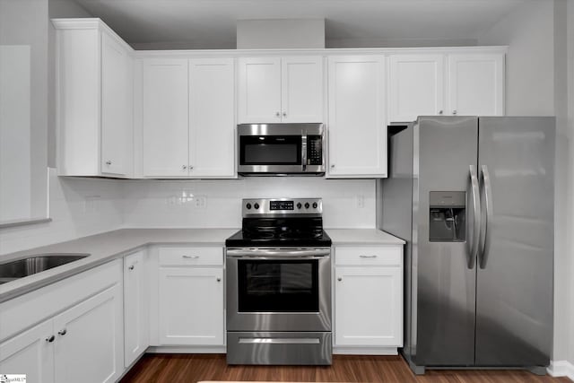 kitchen featuring dark wood-type flooring, white cabinetry, light countertops, appliances with stainless steel finishes, and decorative backsplash