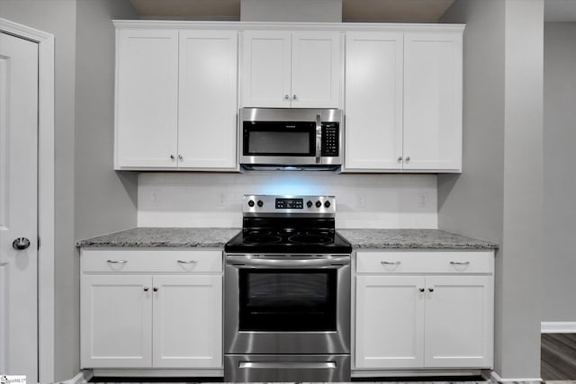 kitchen with appliances with stainless steel finishes, white cabinets, backsplash, and light stone counters