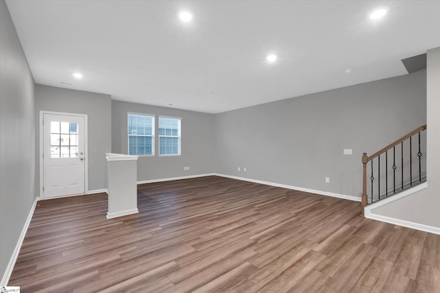 unfurnished living room with stairs, baseboards, wood finished floors, and recessed lighting