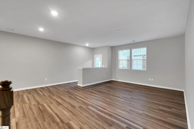 unfurnished room with baseboards, wood finished floors, and recessed lighting