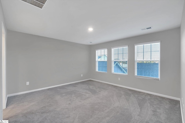 spare room featuring carpet floors, baseboards, and visible vents