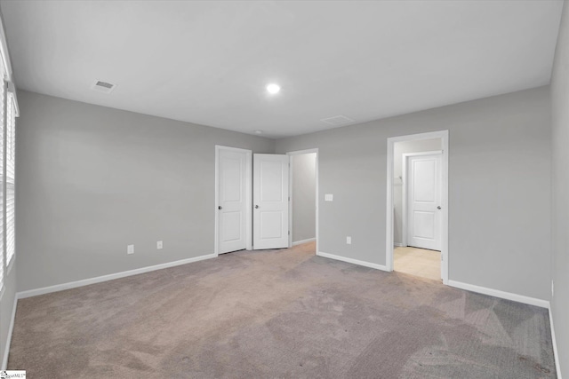 unfurnished bedroom with carpet flooring, visible vents, and baseboards