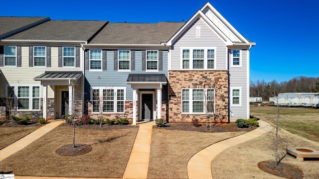 view of property featuring metal roof, stone siding, a shingled roof, and a standing seam roof