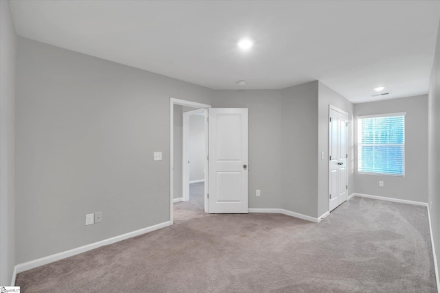 carpeted spare room with visible vents and baseboards