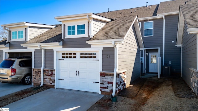 view of front of home featuring a garage, stone siding, a shingled roof, and concrete driveway