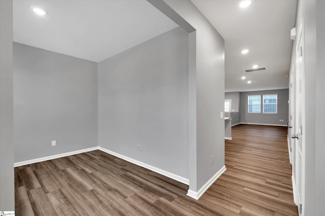 spare room featuring wood finished floors, visible vents, and baseboards