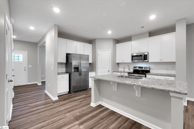 kitchen with appliances with stainless steel finishes, tasteful backsplash, a sink, and wood finished floors