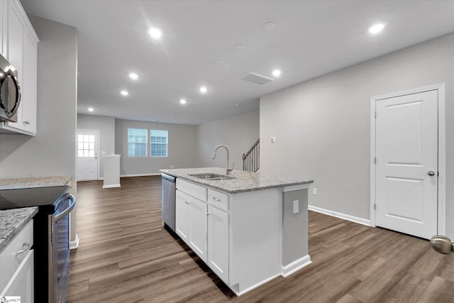 kitchen with appliances with stainless steel finishes, white cabinetry, a sink, and wood finished floors