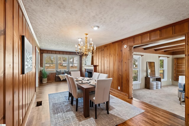 dining room featuring a textured ceiling, a fireplace, light wood-style flooring, and a healthy amount of sunlight