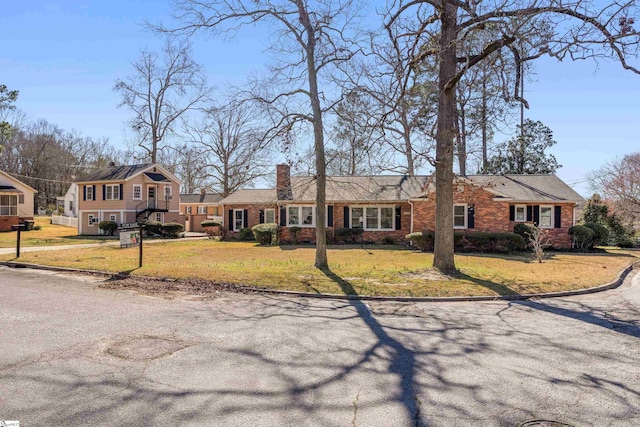 view of front of house featuring a front yard, brick siding, and a chimney