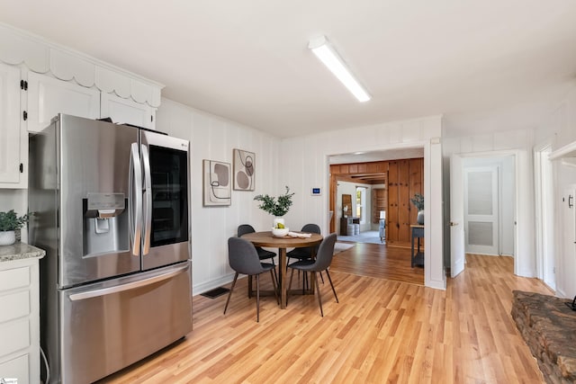 kitchen featuring visible vents, light wood-style flooring, white cabinets, and stainless steel fridge with ice dispenser