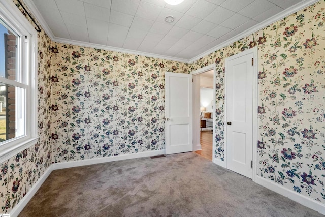 spare room featuring carpet floors, ornamental molding, baseboards, and wallpapered walls