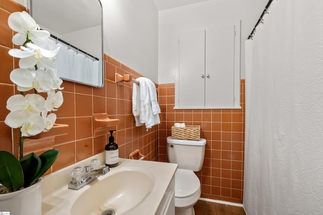 bathroom with a shower with shower curtain, toilet, wood finished floors, vanity, and tile walls