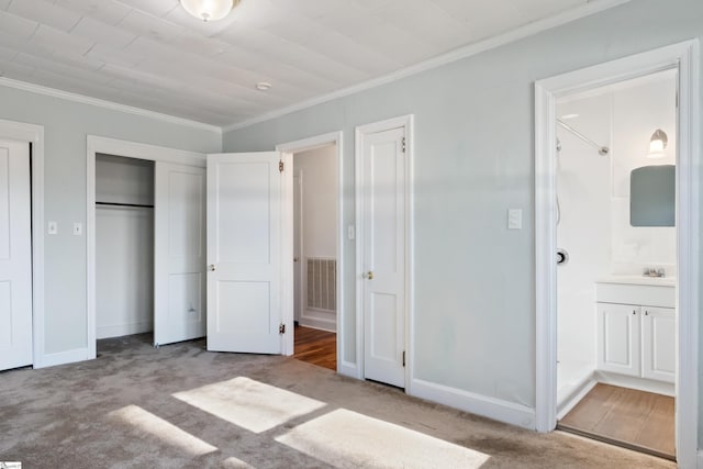 unfurnished bedroom featuring carpet floors, crown molding, visible vents, connected bathroom, and baseboards