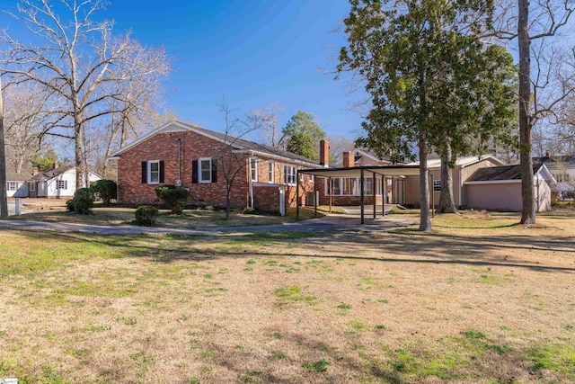 rear view of property featuring a carport, a lawn, and brick siding