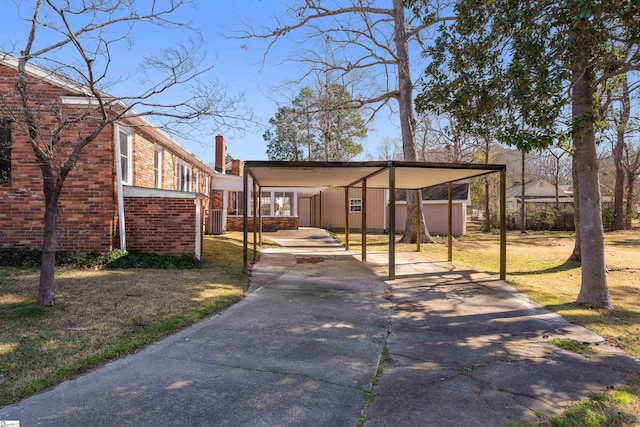 view of front of home featuring a front yard, central AC, concrete driveway, and brick siding