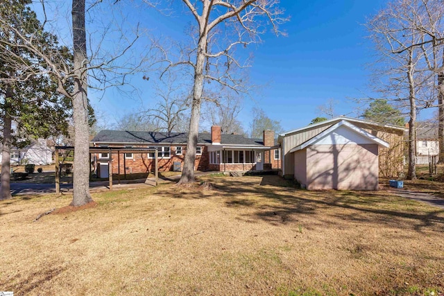 back of house with a chimney, a lawn, and brick siding